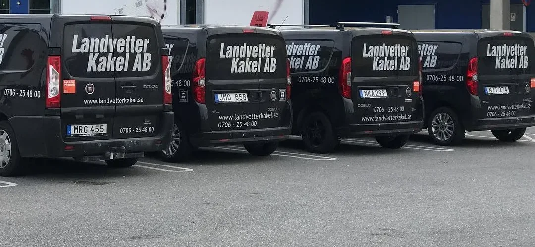 Fem svarta servicebilar med Landvetter Kakel AB:s logga parkerade på rad